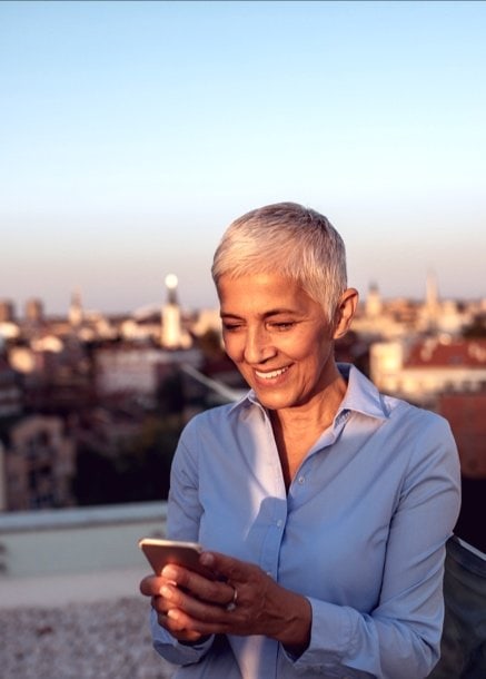 Woman using phone in golden hour city skyline