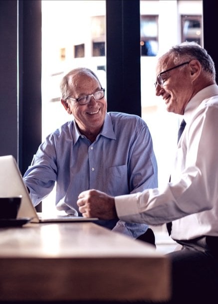 two men happily discussing with computer